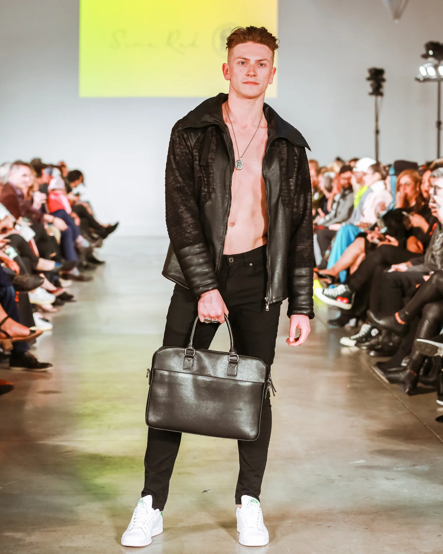 Benjamin Wills walking a runway in a black leather look.