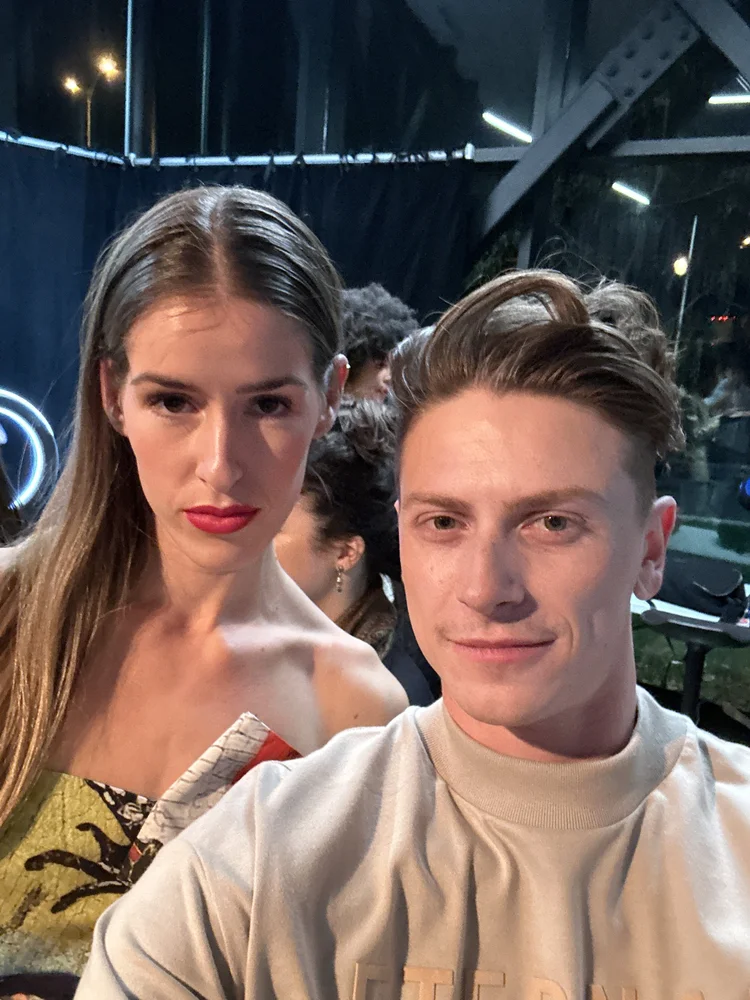 Benjamin Wills with a runway model in golden yellow couture at a fashion week event.