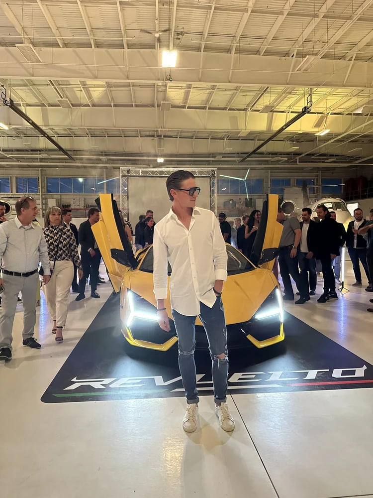 Benjamin Wills at a Lamborghini Revuelto event in front of the car with the doors raised.