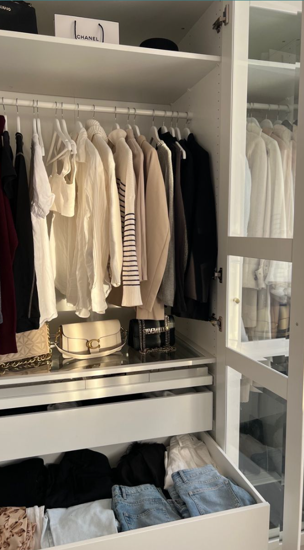 A luxury wardrobe edit with neatly arranged neutrals, denim, and designer bags.