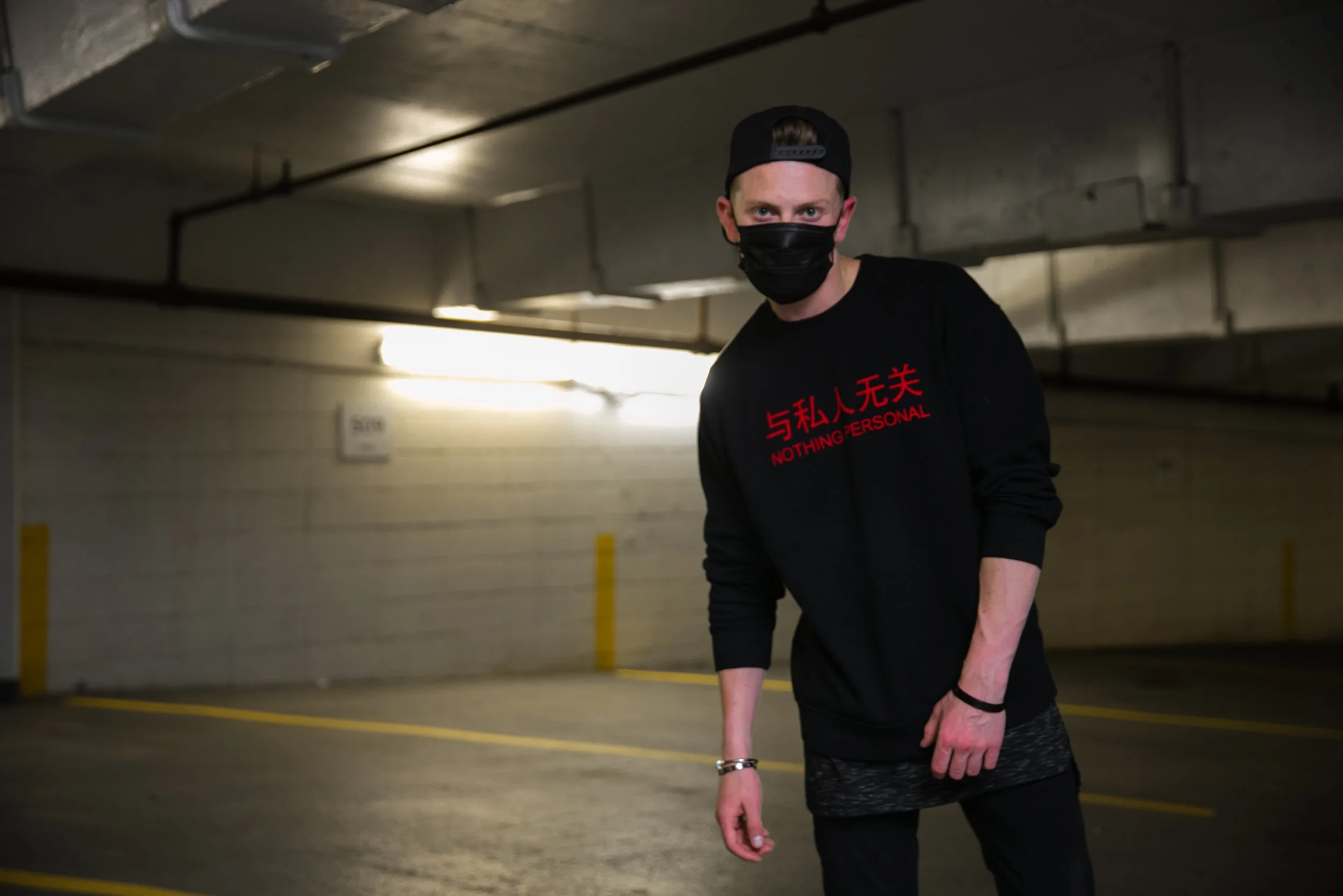 Benjamin Wills in an underground parking editorial wearing a black mask and sweatshirt.